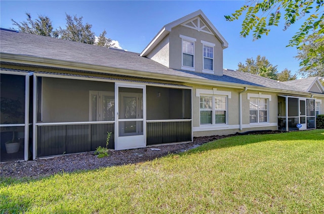 rear view of property featuring a sunroom and a lawn