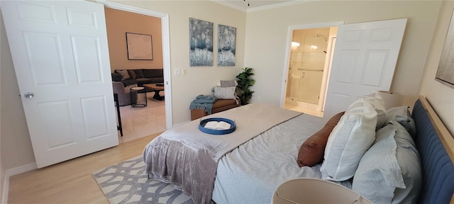 bedroom featuring crown molding, light wood-type flooring, and ensuite bath