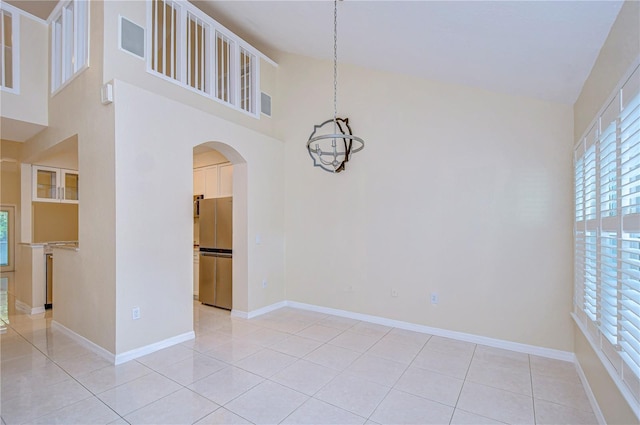 empty room with light tile patterned flooring and high vaulted ceiling