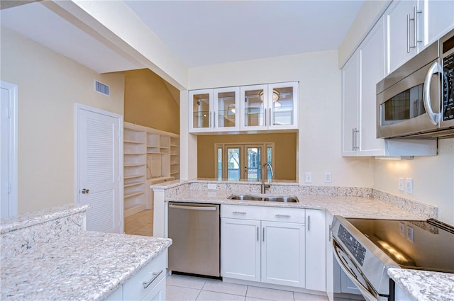 kitchen with light tile patterned floors, stainless steel appliances, sink, and white cabinets