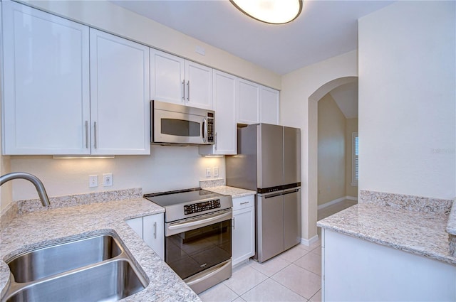 kitchen featuring light stone counters, stainless steel appliances, sink, and white cabinets