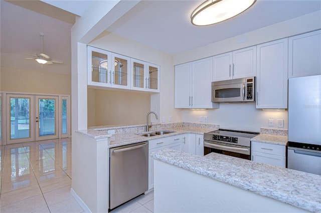 kitchen with sink, white cabinetry, light stone counters, light tile patterned floors, and appliances with stainless steel finishes