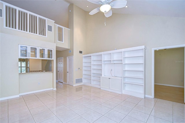 interior space featuring light tile patterned flooring, ceiling fan, and a towering ceiling