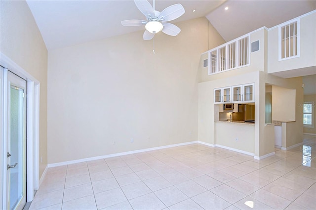 unfurnished living room with ceiling fan, high vaulted ceiling, and light tile patterned floors