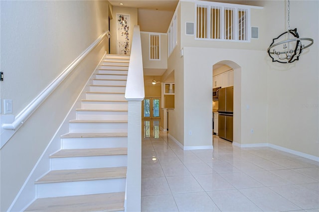 stairway with a towering ceiling and tile patterned flooring