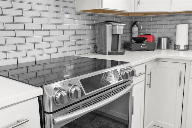 kitchen featuring white cabinetry, stainless steel electric stove, and tasteful backsplash