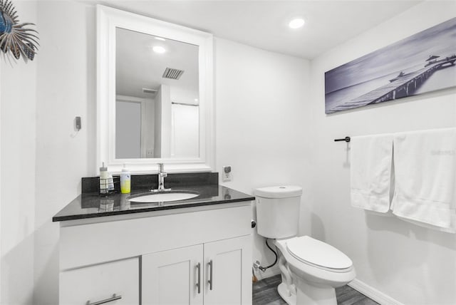 bathroom with hardwood / wood-style floors, vanity, and toilet