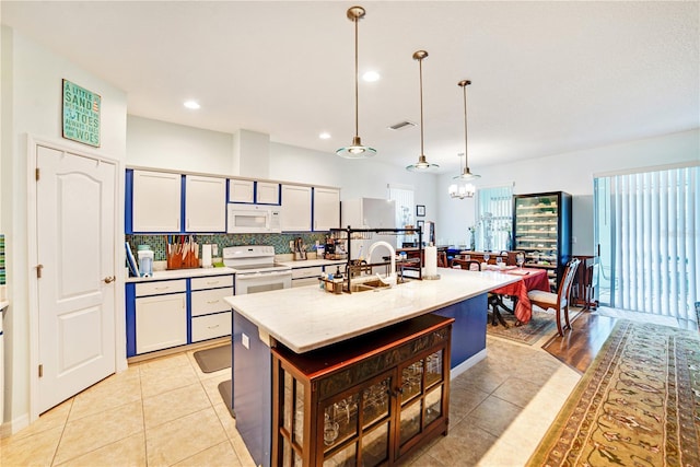 kitchen with backsplash, light tile patterned floors, pendant lighting, and white appliances