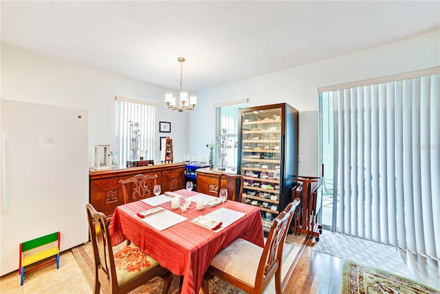 dining area featuring light hardwood / wood-style flooring, a textured ceiling, and an inviting chandelier