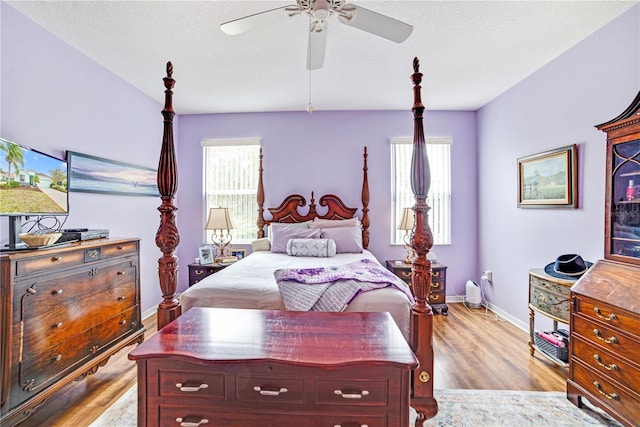 bedroom featuring multiple windows, a textured ceiling, light hardwood / wood-style floors, and ceiling fan