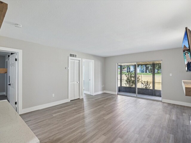 unfurnished living room with a textured ceiling and hardwood / wood-style floors