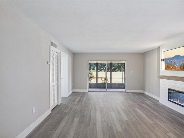 unfurnished living room with wood-type flooring and a textured ceiling