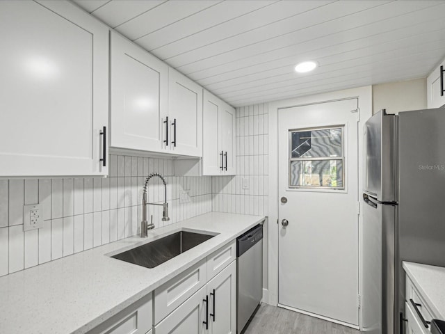 kitchen featuring sink, white cabinetry, stainless steel appliances, light stone countertops, and light hardwood / wood-style floors