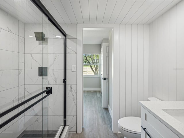 bathroom with vanity, hardwood / wood-style flooring, wooden walls, toilet, and an enclosed shower