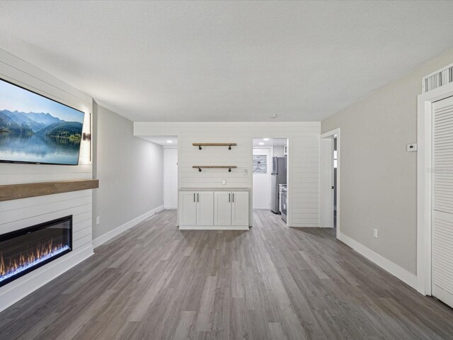 unfurnished living room featuring a textured ceiling, a fireplace, and light wood-type flooring