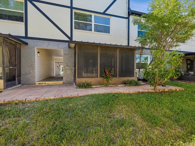 back of property featuring a sunroom, a patio, and a yard