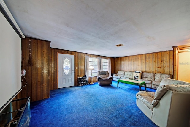 living room featuring wooden walls and dark colored carpet