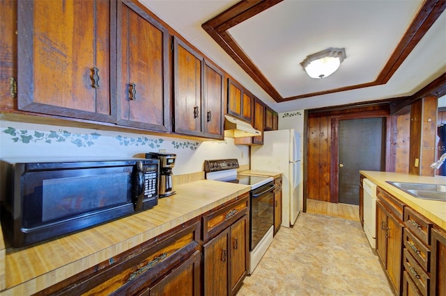 kitchen featuring a raised ceiling, white appliances, and sink