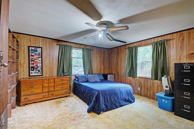 bedroom with ceiling fan, light colored carpet, wooden walls, and crown molding