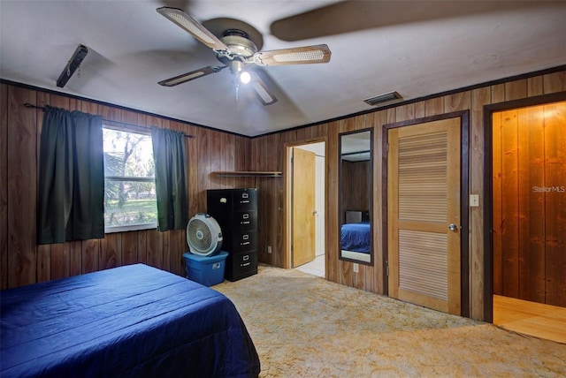 bedroom with light carpet, wooden walls, ceiling fan, and ornamental molding