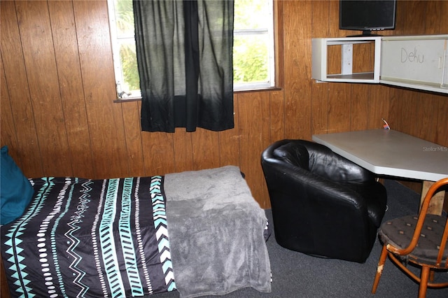 carpeted bedroom featuring multiple windows and wood walls