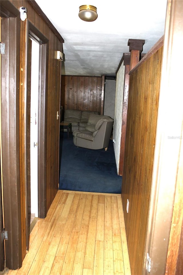 hall with light hardwood / wood-style floors and wooden walls