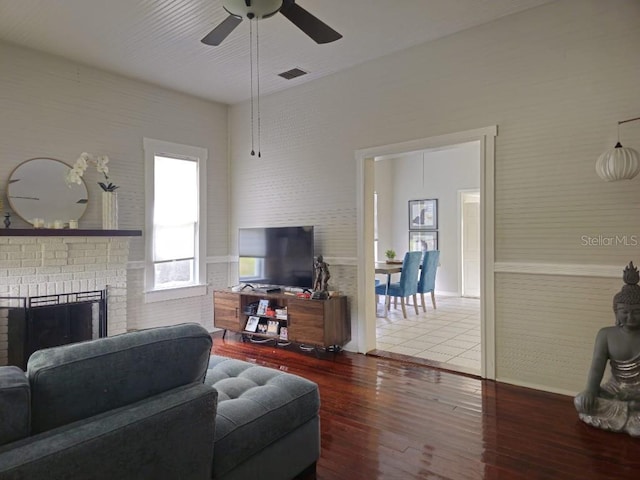 living room with wood-type flooring, ceiling fan, and a fireplace