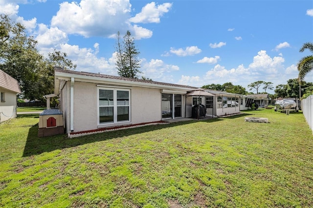 rear view of house featuring a sunroom and a yard