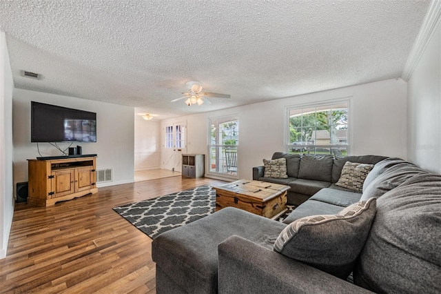 living room featuring a textured ceiling, hardwood / wood-style flooring, ceiling fan, and ornamental molding