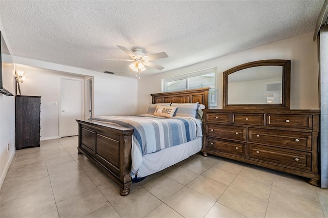 bedroom featuring ceiling fan, light tile patterned floors, and a textured ceiling