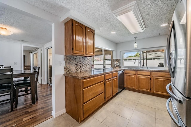 3849 Claremont Dr, New Port Richey, FL 34652 - kitchen with appliances with stainless steel finishes, a textured ceiling, brown cabinets, a sink, and decorative backsplash