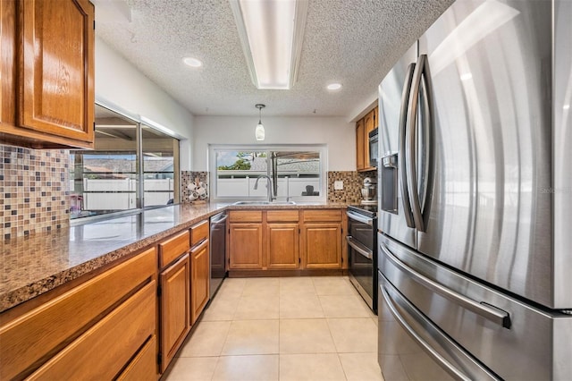 3849 Claremont Dr, New Port Richey, FL 34652 - kitchen featuring stainless steel appliances, brown cabinetry, a sink, tasteful backsplash, and a textured ceiling