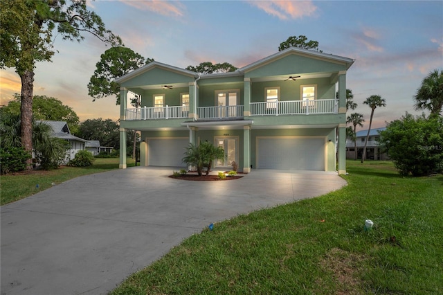 beach home with ceiling fan, a garage, a porch, and a yard