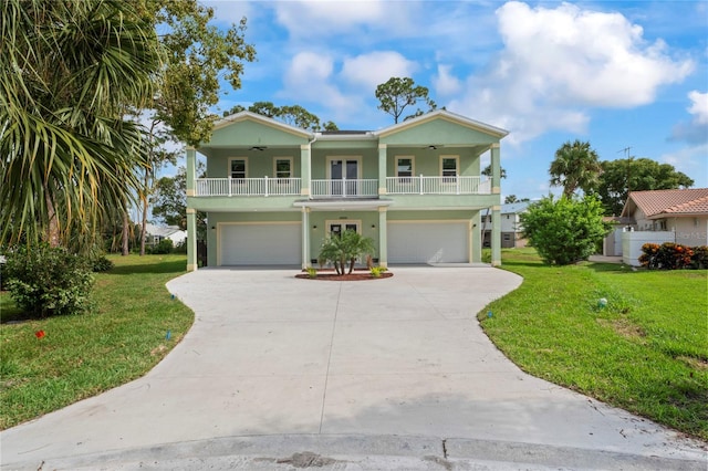 raised beach house featuring a front yard, a porch, and a garage