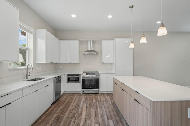 kitchen featuring sink, white cabinetry, hanging light fixtures, wall chimney range hood, and appliances with stainless steel finishes