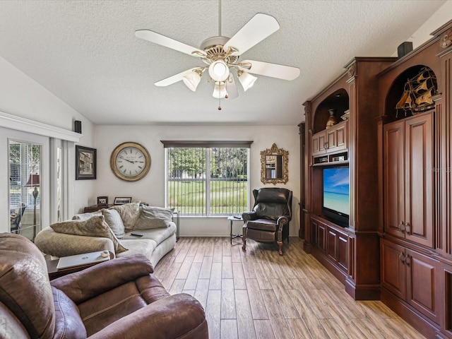 living room with lofted ceiling, light hardwood / wood-style floors, ceiling fan, and a textured ceiling