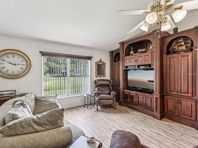 living room with a textured ceiling, light hardwood / wood-style floors, and ceiling fan