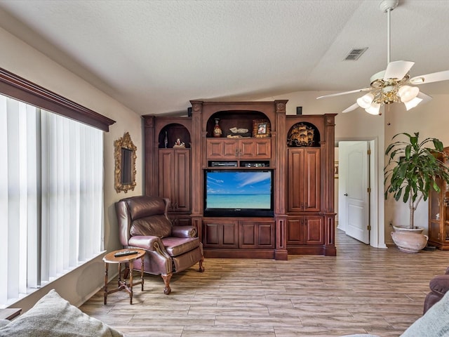 sitting room featuring light wood-type flooring, lofted ceiling, ceiling fan, and a textured ceiling