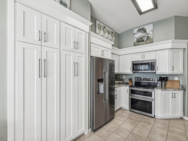 kitchen featuring light stone counters, light tile patterned flooring, stainless steel appliances, and white cabinets