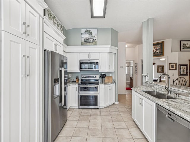 kitchen featuring light stone counters, white cabinets, light tile patterned floors, sink, and appliances with stainless steel finishes