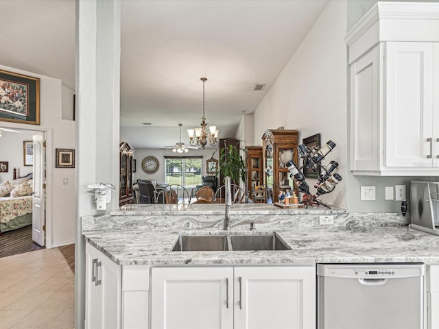 kitchen with light stone counters, white dishwasher, sink, a chandelier, and white cabinetry