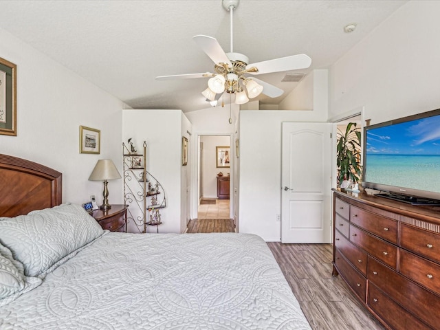 bedroom with ceiling fan, lofted ceiling, and light hardwood / wood-style floors