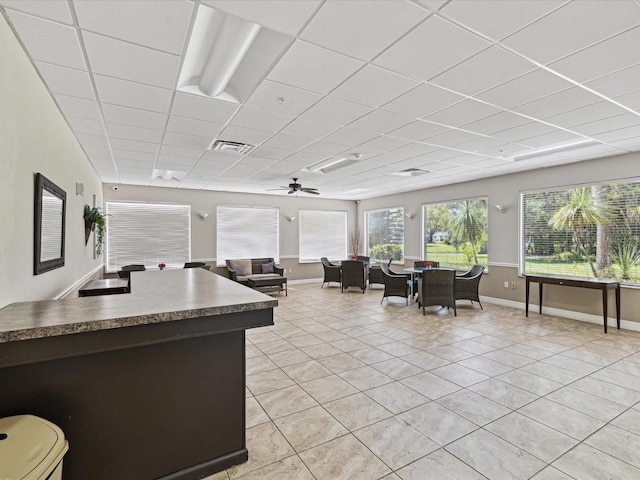 interior space with a drop ceiling, ceiling fan, and light tile patterned floors