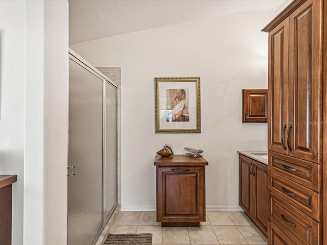 bathroom with vanity, lofted ceiling, tile patterned flooring, and a shower with door