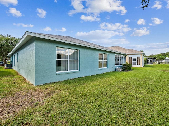 back of house featuring a lawn and central air condition unit