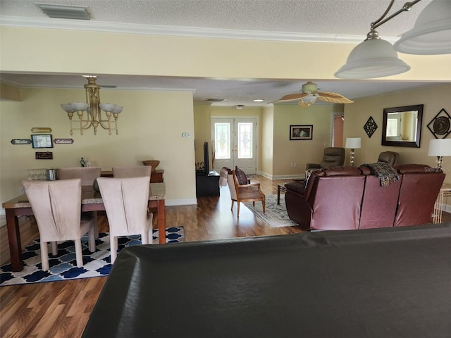 living room featuring a textured ceiling, crown molding, french doors, and hardwood / wood-style flooring