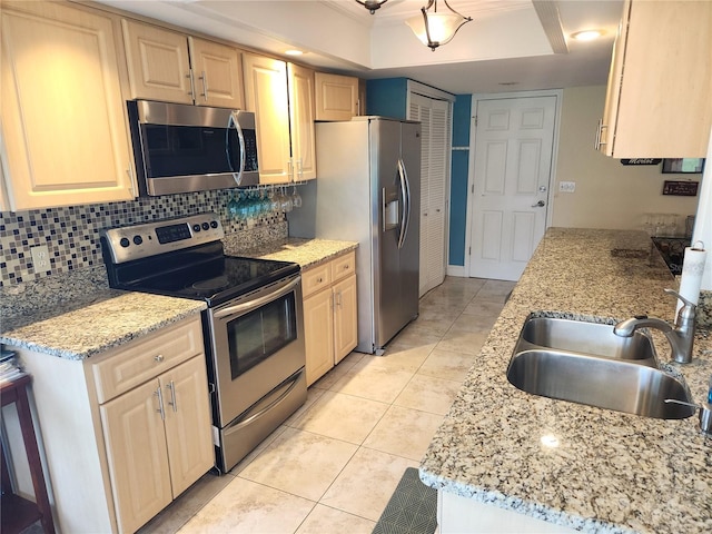 kitchen with light stone counters, sink, decorative backsplash, appliances with stainless steel finishes, and light brown cabinetry