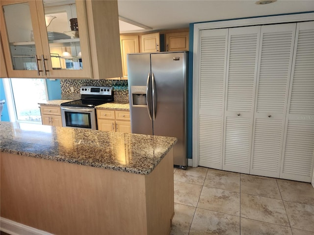 kitchen featuring dark stone countertops, light brown cabinetry, stainless steel appliances, and light tile patterned floors