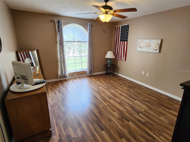 unfurnished room with ceiling fan, a textured ceiling, and dark wood-type flooring