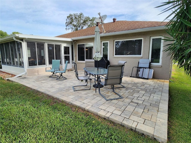 back of property with a sunroom, a patio, and a lawn